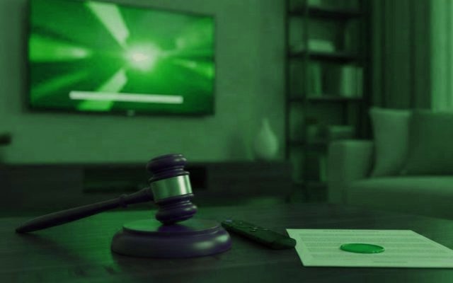 A judge gavel, a streaming remote and a sealed document on a coffee table in front of a TV