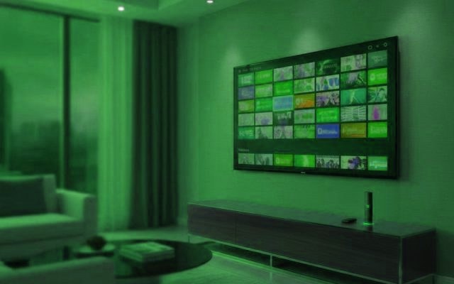 A living-room TV showing an IPTV channel guide with a streaming stick on the console
